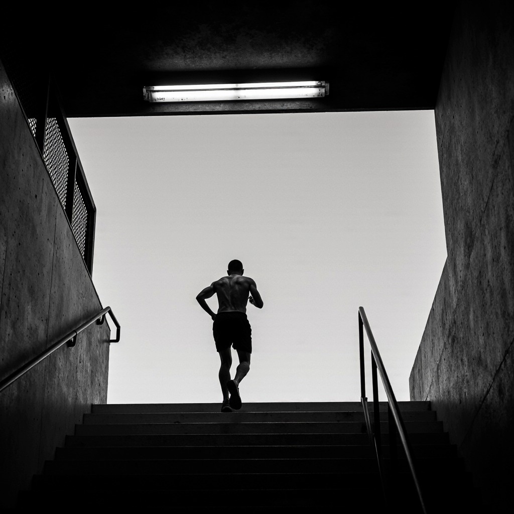 Coureur montant les escaliers vers la lumière, noir et blanc